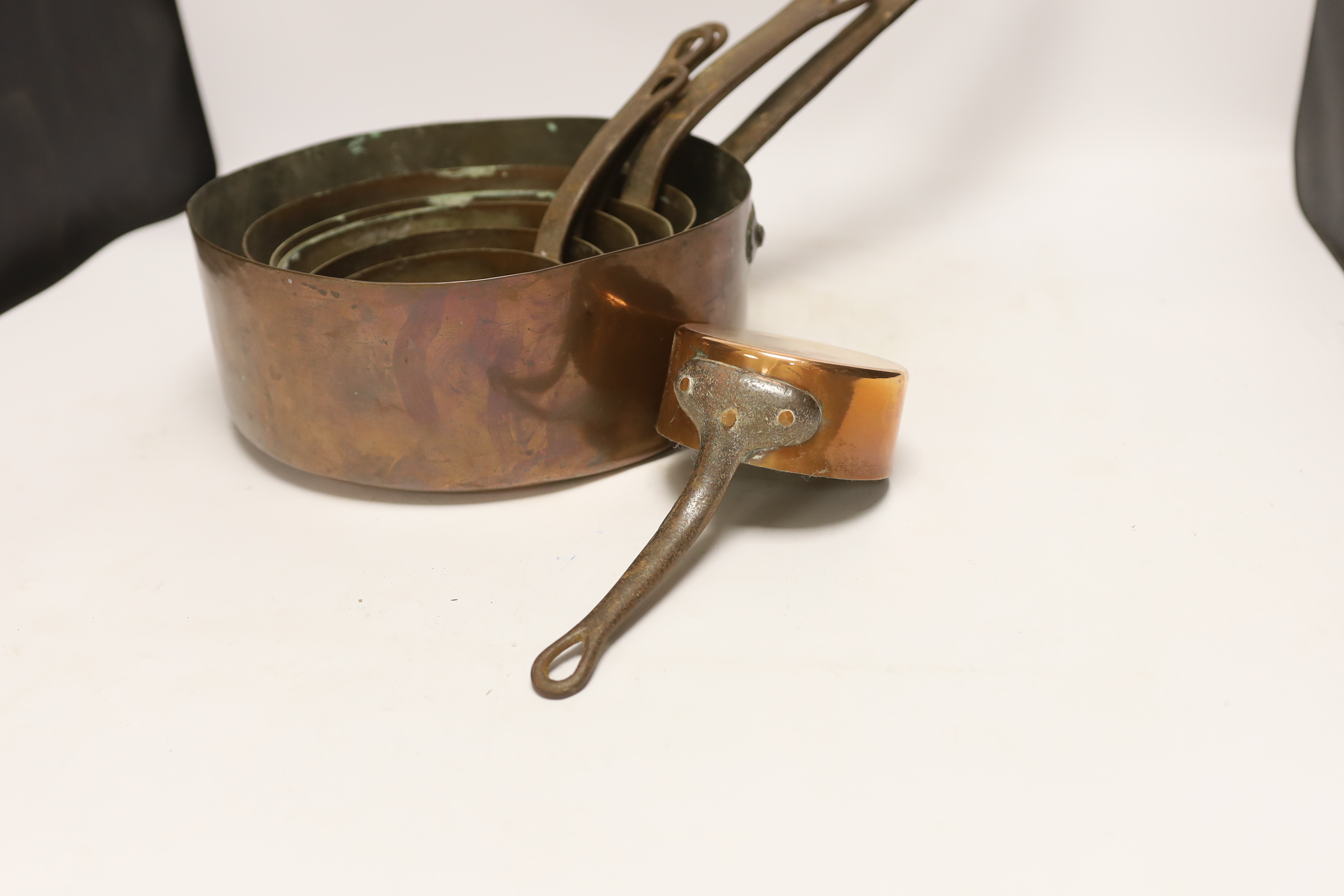 Six graduated copper saucepans, largest 27cm diameter